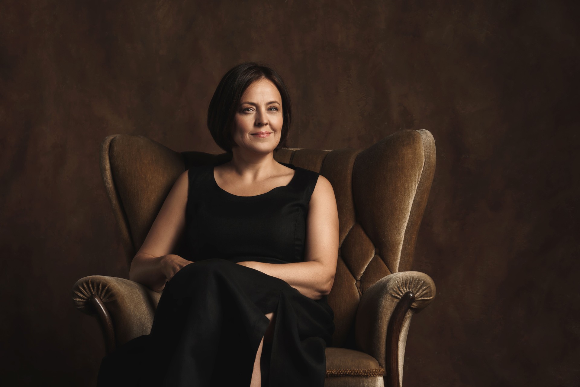 Beautiful middle aged woman sitting in a brown velvet armchair